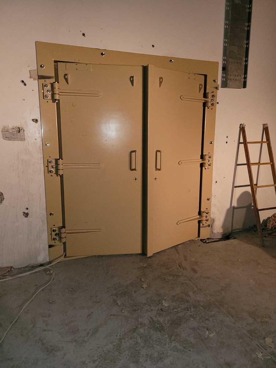 Double-leaf ammunition depot access door with heavy hinges, shown during site installation